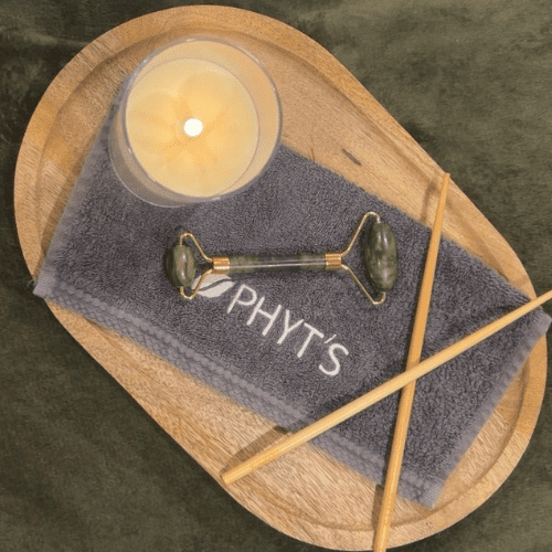 Accessoires de soin visage Phyt’s avec rouleau en pierre, serviette et bougie pour un rituel naturel et relaxant en institut à Nantes.